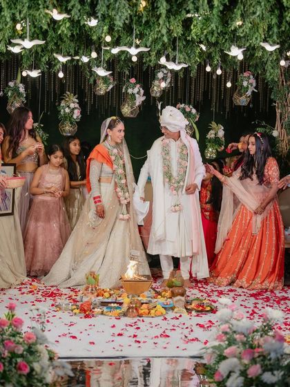 A moment of togetherness under a canopy of green and white. This mandap design incorporates hanging bird motifs and floral arrangements for a whimsical, garden-like feel.