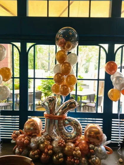 A close-up of the "Sweet 16" balloon centerpiece, featuring a large number 16 foil balloon and a mix of chrome and metallic colors.