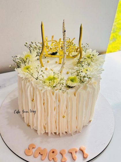A cake that blooms with love and elegance. This design features a textured buttercream finish and is adorned with fresh baby's breath and daisies.