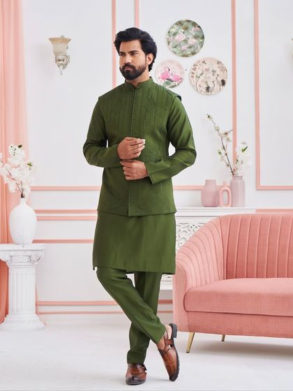 This olive green kurta set, paired with a structured, subtly embroidered jacket, offers a unique and stylish color choice for wedding festivities. It is a modern ensemble rooted in traditional aesthetics.