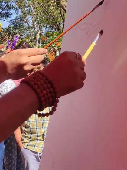 Two brushes, one canvas. A close-up of the moment we began the collaborative acrylic landscape.