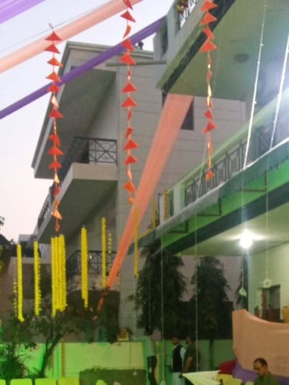 An outdoor tent setup with overhead draping and hanging marigold strings. This is a great way to create a festive zone in a lawn or backyard for pre-wedding events.