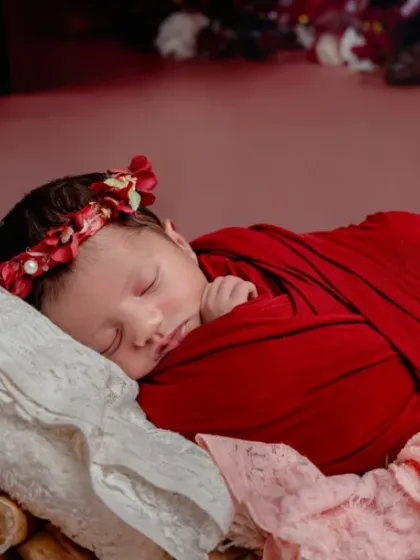 Wrapped in red and resting in love. This rustic setup uses a log-pile prop and a bold red wrap for a unique, nature-inspired look.