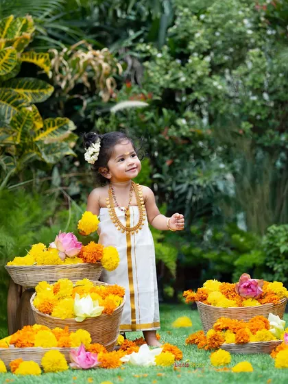 Taking the celebration outdoors to capture the vibrant spirit of Onam. This beautiful shot of a little girl in traditional attire amidst baskets of marigolds showcases how I can create stunning festive portraits in a natural setting.
