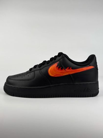 A custom black Nike Air Force 1 with a fiery swoosh on one shoe.
