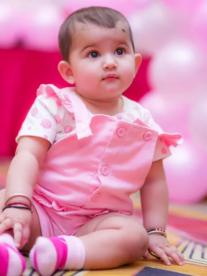 An adorable baby girl in a pink outfit, captured during a moment of quiet observation. I photograph a mix of energetic and calm moments to show all sides of your child.