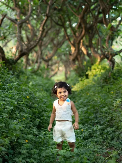 This toddler looks so confident and happy exploring this magical green pathway. I love capturing their adventurous spirit during outdoor photoshoots.