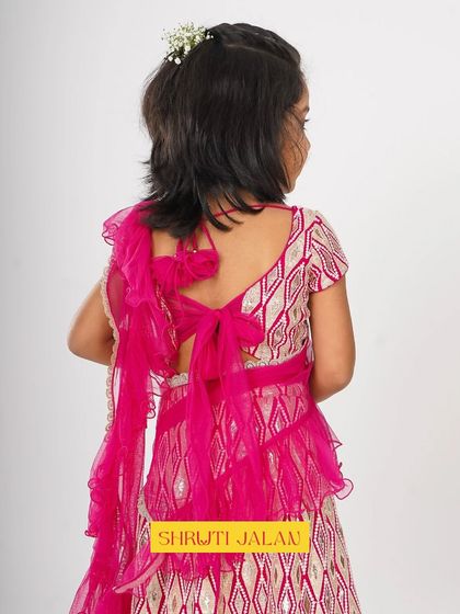 The back of an outfit should be just as beautiful as the front. This fuchsia pink lehenga features a lovely bow tie and a pre-draped ruffled dupatta, adding a touch of modern elegance to a traditional look.