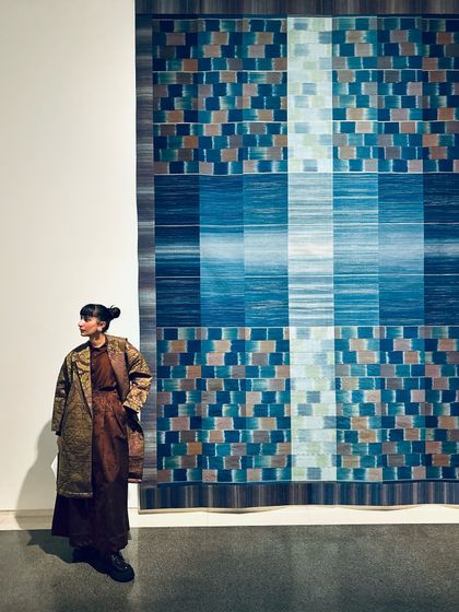 Posing next to a stunning textile art piece in Japan, a moment where fashion meets art.