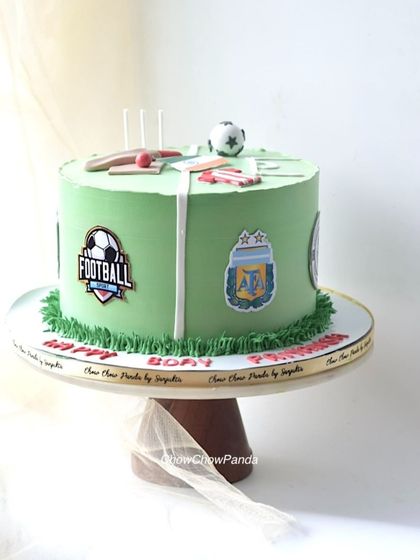 A cake for a football lover, featuring a green "pitch" and logos of their favourite teams. This Chocolate Truffle cake is topped with a mini football and cricket bat.
