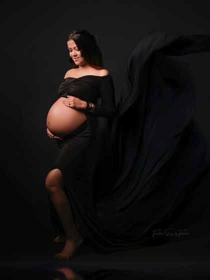 A dramatic and elegant solo portrait in a black flowing gown against a black backdrop. This classic fine art style is truly timeless.