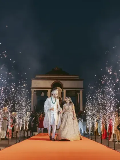 The couple's grand entrance on a red carpet, flanked by guests and cold pyro fountains. This is how I turn a simple walk into a show-stopping moment.