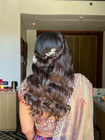 A side view of the half-updo, highlighting the soft waves and the delicate baby's breath woven into the braid.