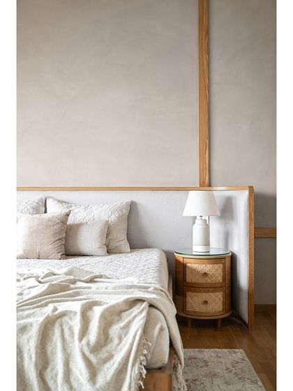A close-up of the bed and the custom rattan nightstand, highlighting the blend of clean lines and natural, tactile materials.