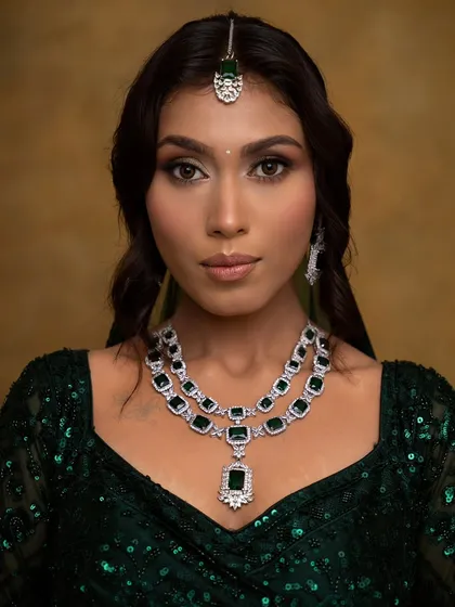 A close-up of a glamorous look perfect for a cocktail party or wedding reception. I used a blend of gold and brown eyeshadows to create a soft glam eye, paired with defined brows and a neutral lip, ensuring the focus remains on the client's radiant skin and stunning emerald jewelry.