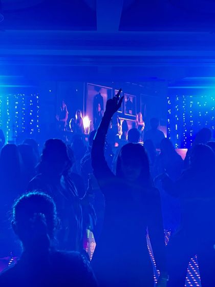 A silhouette of the crowd under blue lights, with one person's hand in the air. This image captures the collective energy of a great party.