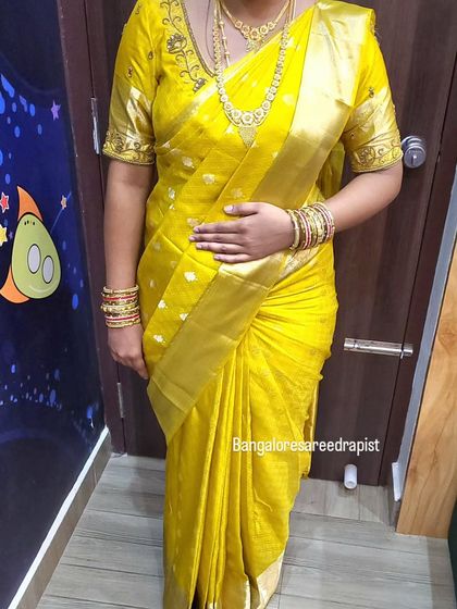 A full-length view of the gold saree drape. The body-fit style ensures a smart silhouette while maintaining a traditional feel appropriate for the event.