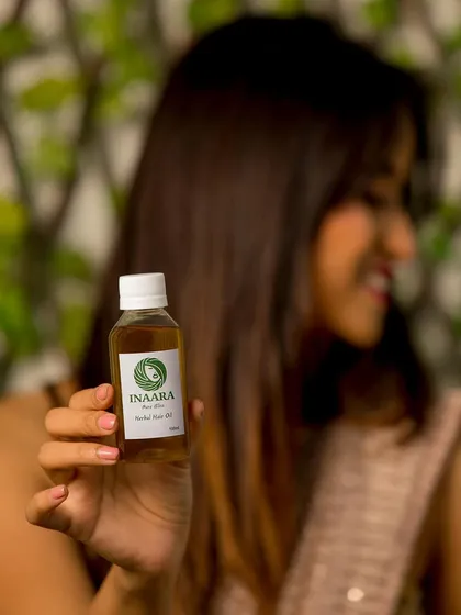 Holding a bottle of my Pure Bliss hair oil. It's a promise of handmade quality and natural ingredients for your hair regrowth and hair fall control journey.