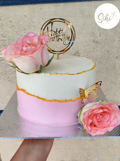 The beauty lies in simplicity. This two-toned pink and white cake is elegantly decorated with a gold fault line, fresh pink roses, and a delicate gold butterfly.