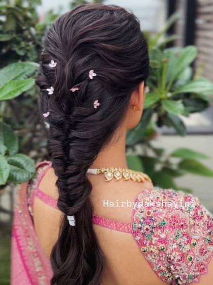 A beautiful fishtail braid with a unique twist, decorated with small flower-like pins for a modern and chic look.