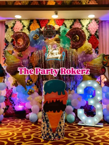 Welcome to Candyland! I love creating these sweet themes with giant donut and ice cream props, a colorful balloon arch over a shimmer wall, and a large light-up number for the birthday child's age. It's a vibrant and fun setup for any party.