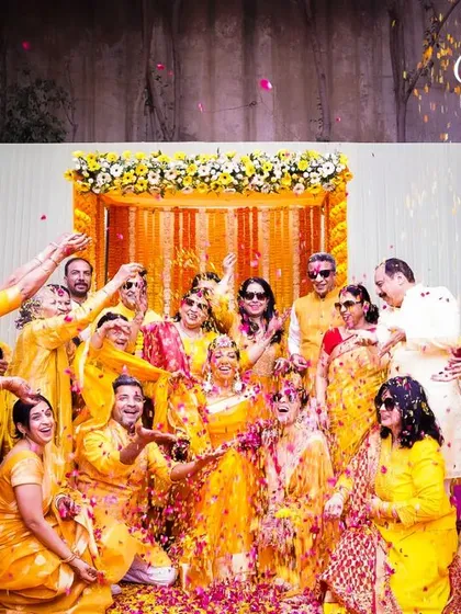 A shower of flower petals and happiness. This group photo captures the collective joy of the family and friends celebrating the Haldi ceremony.