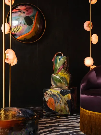 The Bocci 84 series styled alongside vibrant, artistic furniture. The warm, diffused light from the pendants complements the rich colors and textures of the surrounding decor.
