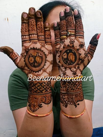 A full-hand design with peacock mandalas and a jaali pattern on the wrists.