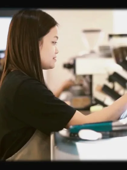 A barista focused on her craft at the espresso machine. The dedication of our team is key to our quality.