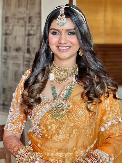 A full view of the Phera look. The orange lehenga is paired with soft, glowing makeup and beautiful, voluminous curls.