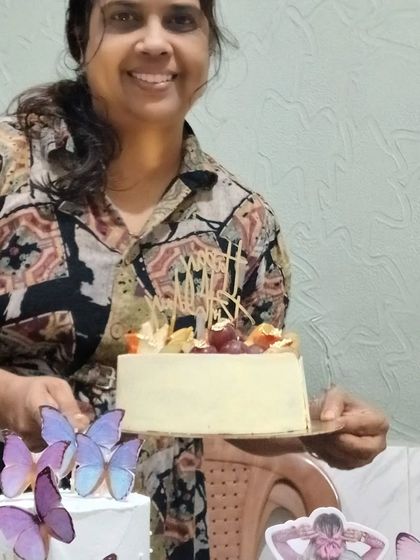 Me holding a fresh fruit cake, alongside two other butterfly-themed cakes.