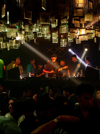 A wide shot of the DJ booth and the unique ceiling decor at M Bar, with spotlights focused on the music.