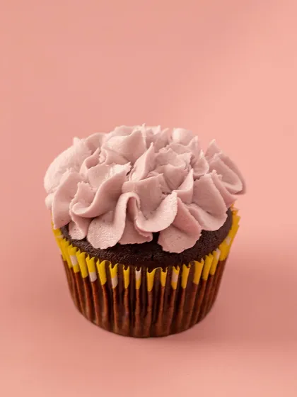 This cupcake features a rich Belgian chocolate base and is topped with beautifully piped lavender-colored vanilla buttercream, creating a delicate, petal-like effect.