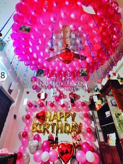 To create an unforgettable birthday surprise, I transformed this entire room with hundreds of pink balloons covering the ceiling. The setup includes 'Happy Birthday' foil balloons and hanging photos for a personal touch that makes the moment truly special.