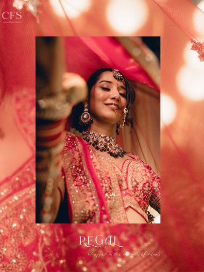 "Regal." A captivating shot of a bride under her red veil. The warm lighting and her confident smile make this a powerful and statement-making bridal portrait.