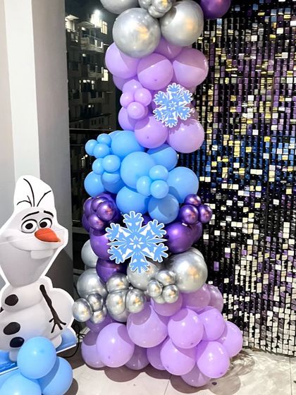 A close-up of the Olaf cutout and the balloon column for a Frozen-themed party, set against a silver sequin backdrop.