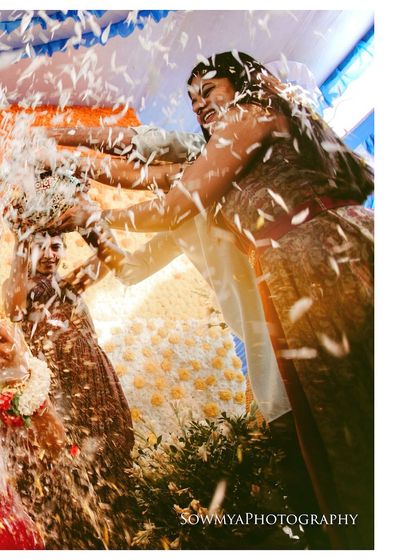 A joyful, high-energy moment from a wedding celebration, with guests showering the couple with petals.