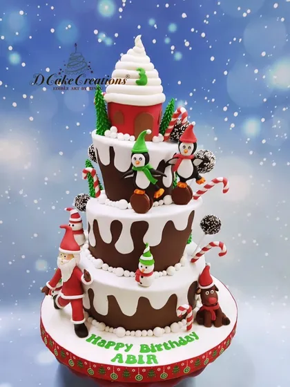 A grand four-tier chocolate drip cake for a Christmas birthday, decorated with penguins, elves, and Santa Claus.