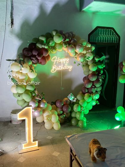 A view of the jungle-themed balloon arch and light-up number '1' under green ambient lighting.