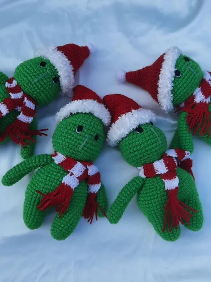 A group of green Grinch-like creatures wearing Santa hats and scarves, a fun and festive creation for Christmas.