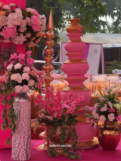 A close-up of the decor details, featuring traditional stacked pots and a 'diya' sculpture in pink and gold, surrounded by beautiful floral arrangements that tied the whole look together.