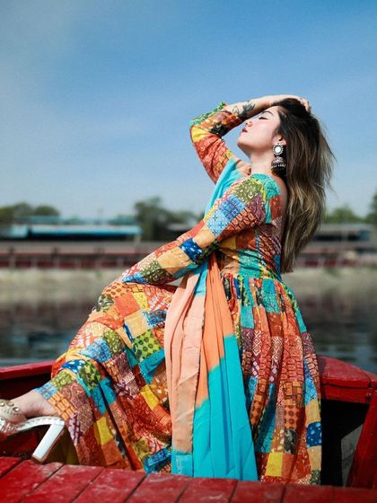 A full-length shot showing the model's complete look, including her heels, as she relaxes on the boat.