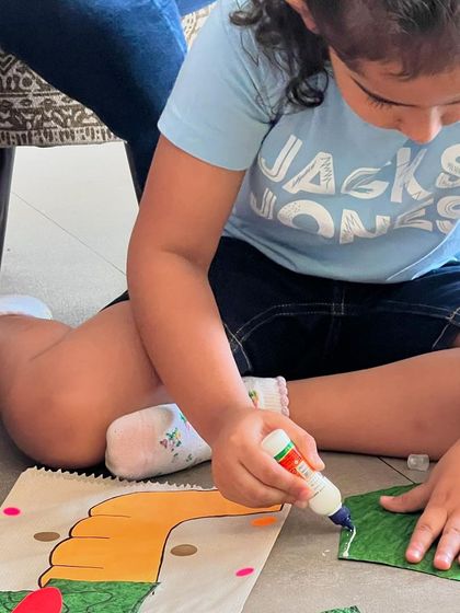 A close-up of a child deeply focused on making her dragon paper bag puppet. These moments of quiet concentration and creativity are just as magical as the loud, giggly ones.
