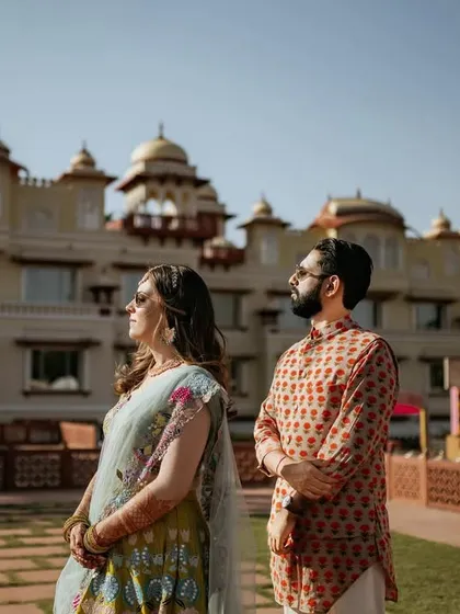 A stylish portrait of the couple against the magnificent facade of a heritage palace. Their modern-meets-traditional outfits and confident poses create a powerful and fashionable pre-wedding image.
