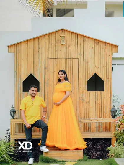 A stylish portrait of a couple in front of a modern, rustic wooden cabin backdrop.