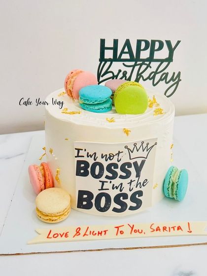 For the boss lady in your life. This cake makes a statement with the "I'm not bossy, I'm the boss" plaque, surrounded by colorful macarons for a touch of fun and elegance.
