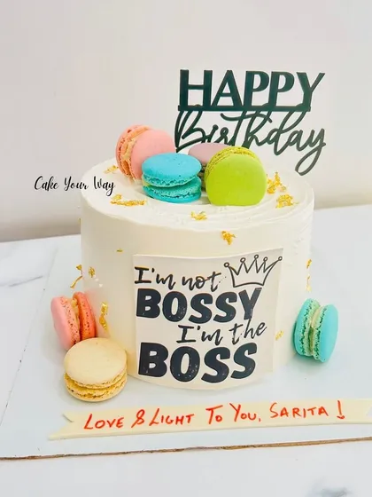 For the boss lady in your life. This cake makes a statement with the "I'm not bossy, I'm the boss" plaque, surrounded by colorful macarons for a touch of fun and elegance.