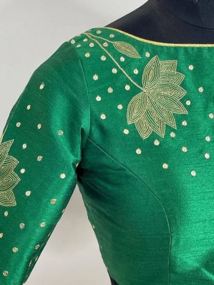 Serving looks in this stunning green blouse. The delicate lotus flower, hand-embroidered with golden thread, adds a touch of luxury and confidence to this beautiful piece.