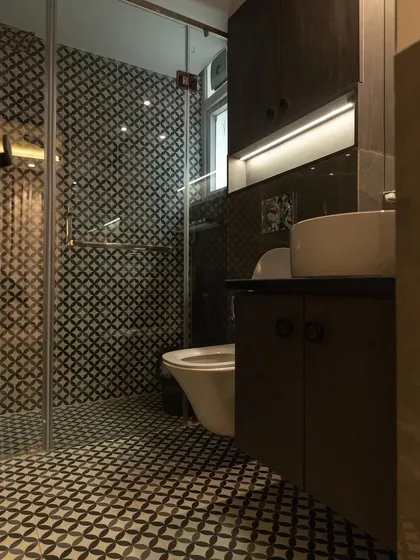This compact bathroom uses patterned tiles on both the floor and the shower wall to create a bold, unified statement. The dark wood vanity and glass shower door complete the modern, stylish look.
