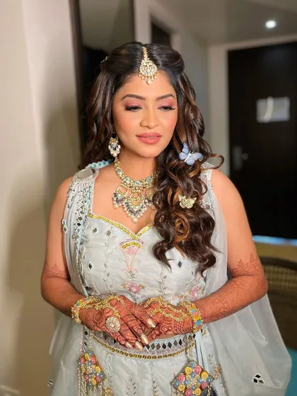A pink affair for Krisha's haldi look to perfectly complement her powder blue outfit. The butterfly hair accessories add a whimsical touch.